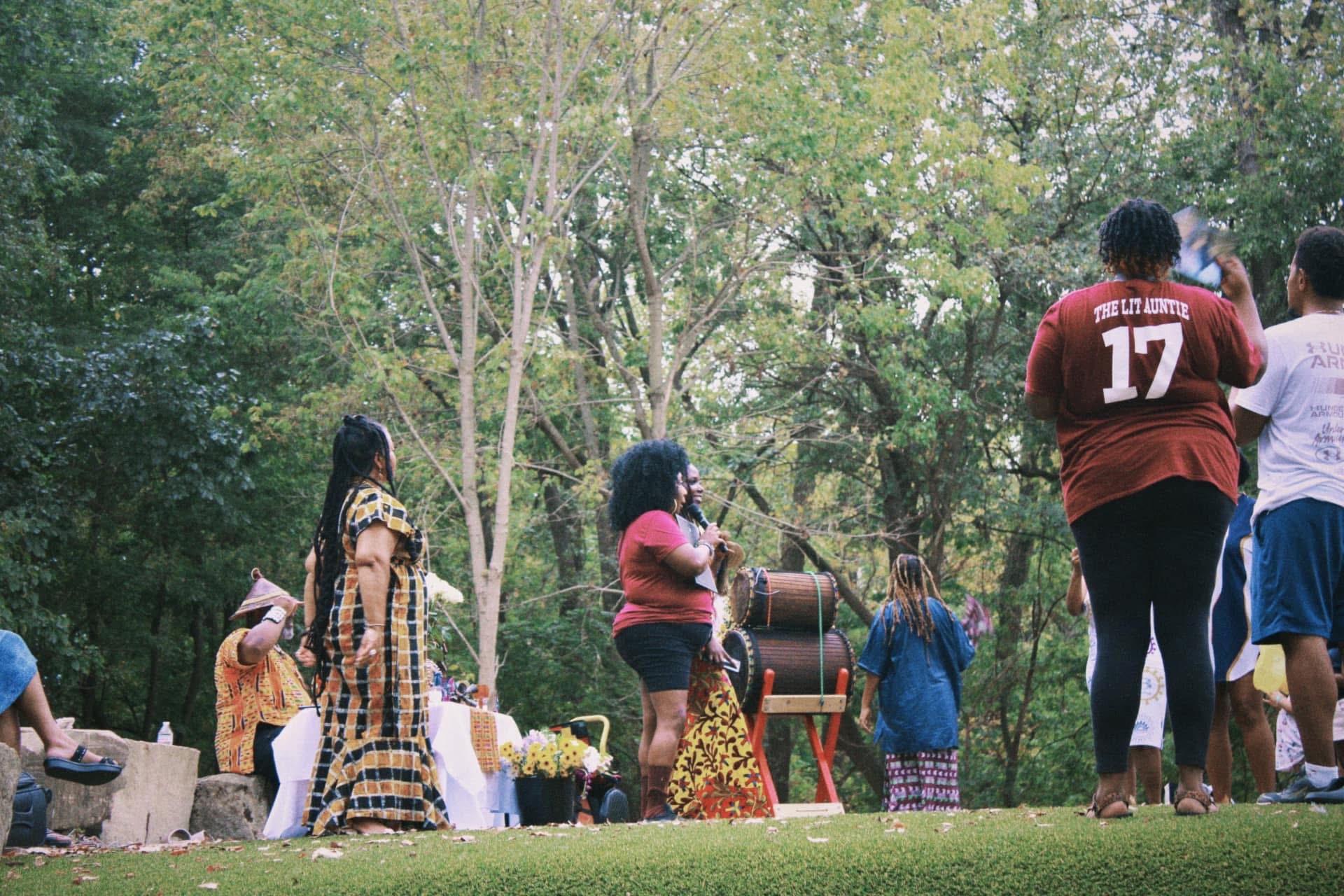 Elders, drummers, and aunties holding ceremony with djembes in the trees