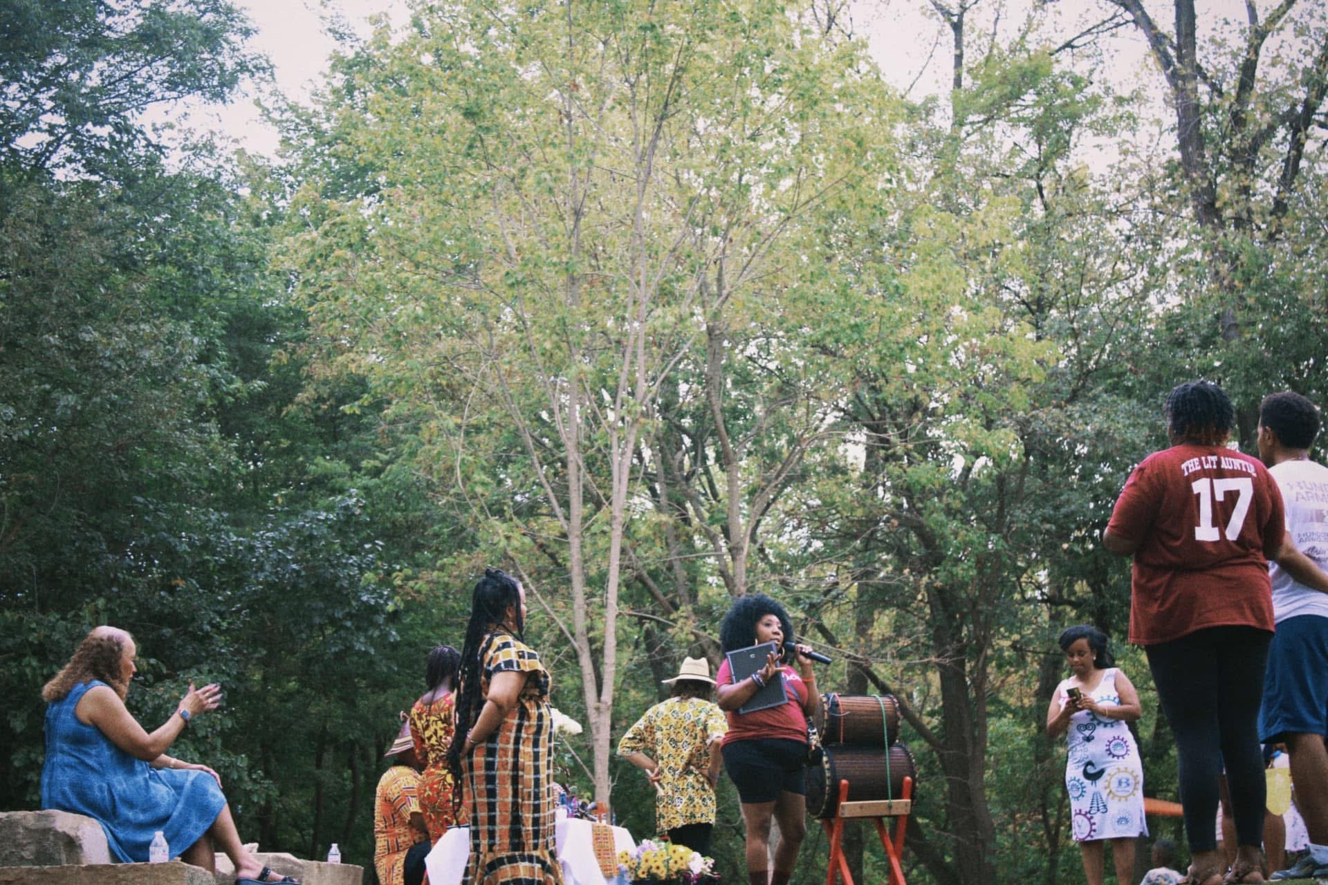A speaker on the microphone leading the gathering beneath green canopy