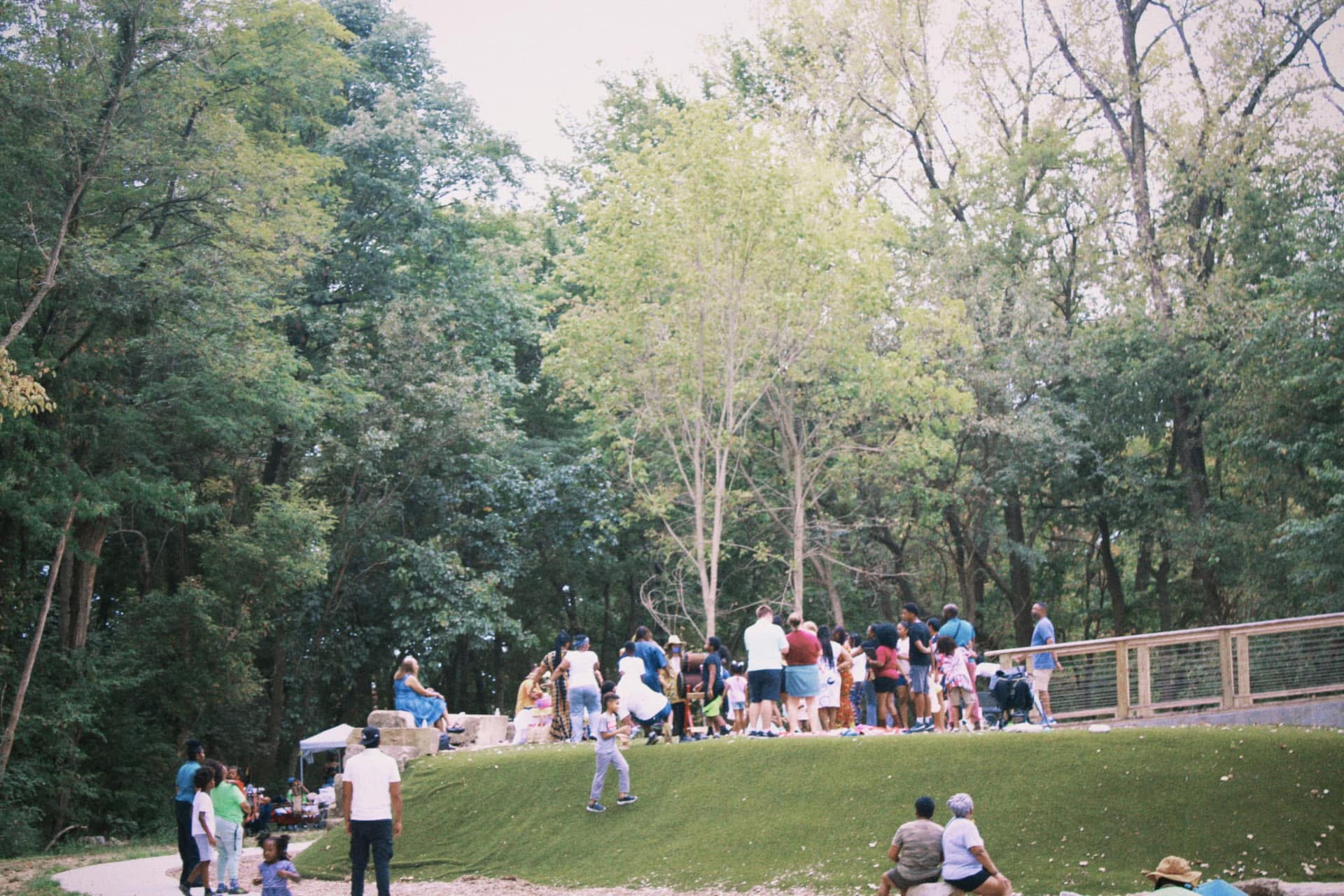 A wide view of the community gathered on a green bluff at golden hour