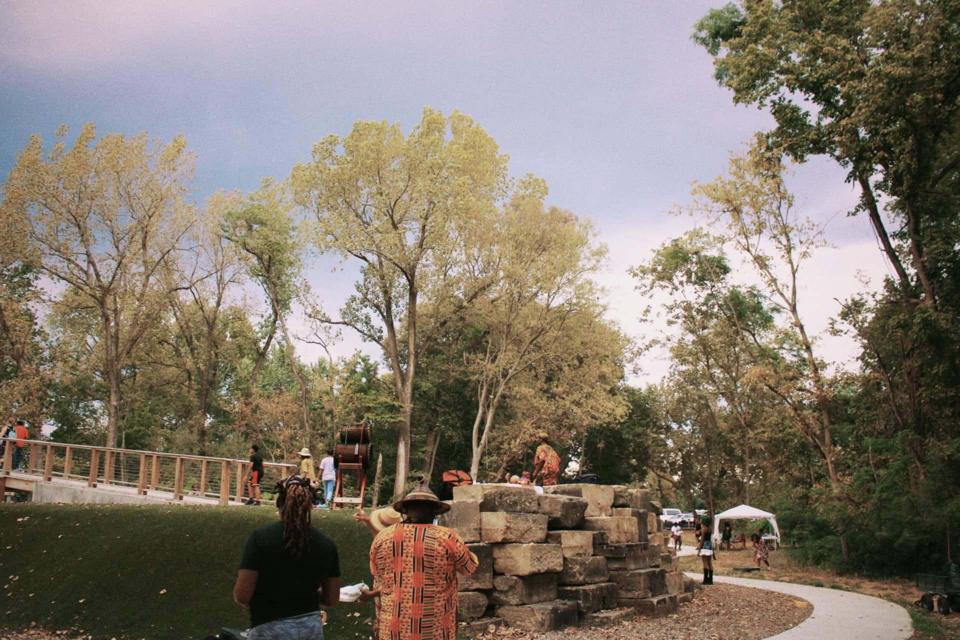 Drummers and elders gathered around a stone altar beneath cottonwood trees